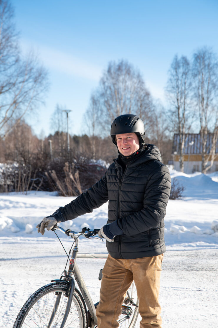 Kaupungin lakimies Mikko Lindroos taluttaa pyörää talvimaisemassa.