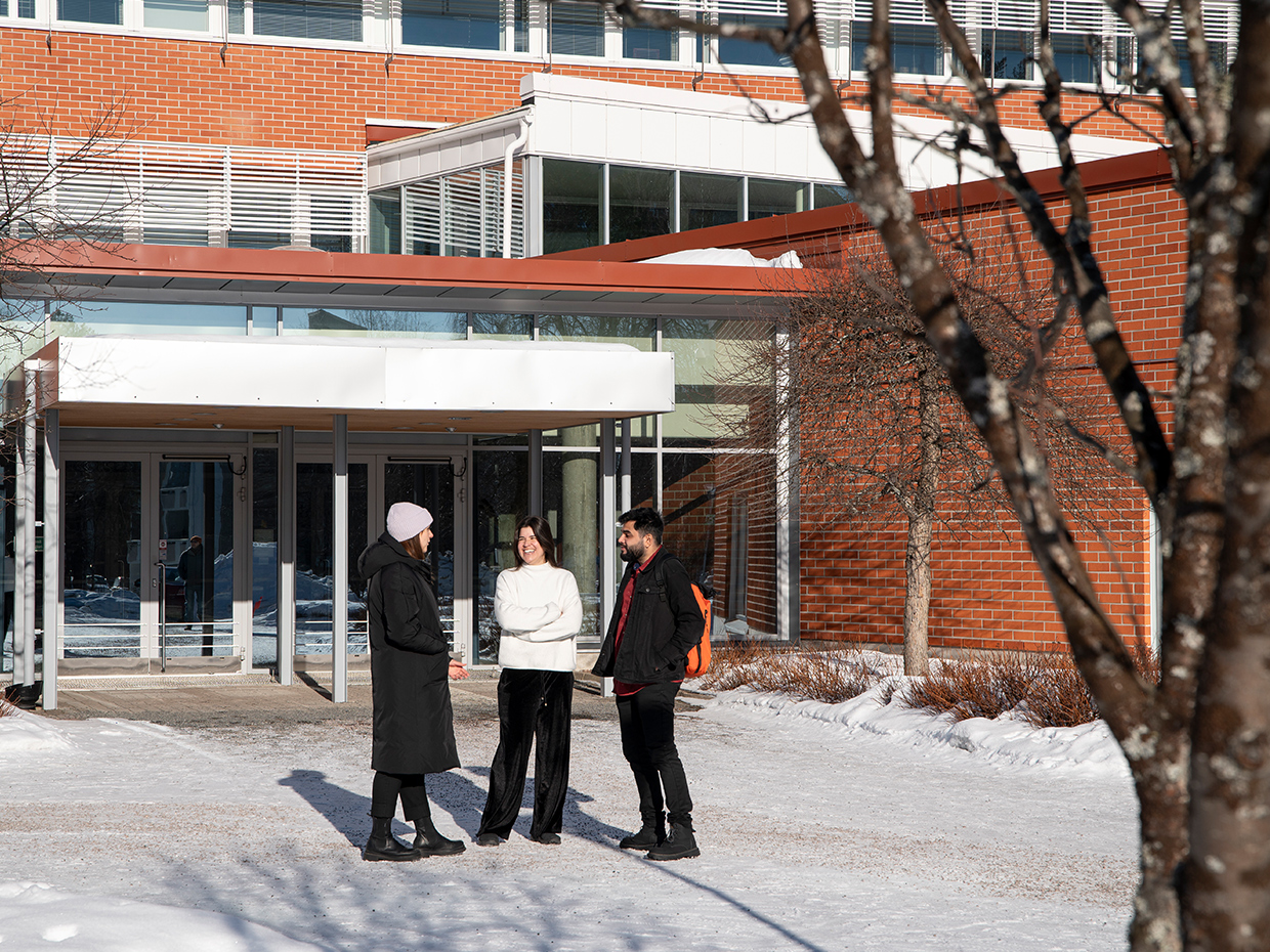 Opiskelijoita seisomassa taiteiden tiedekunnan edustalla