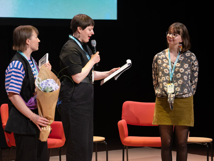Julia Rapo, Anna Möttölä ja Jutta Ekman seisovat tapahtumalavalla.