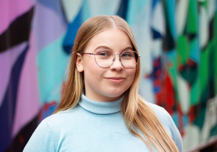 LYYn puheenjohtaja silmälaseissa ja poolopaidassa graffittiseinän edessä.
