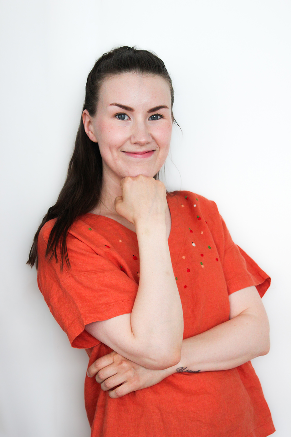 Eveliina Muotkavaara seisoo seinää vasten oikea käsi nostettuna leuan alle.