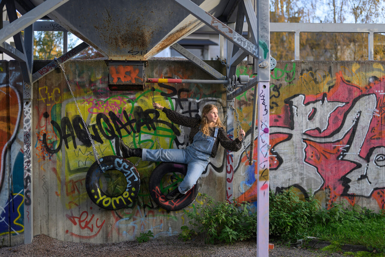Emmi Kairenius temppuilee värikkään graffitiseinän edessä.