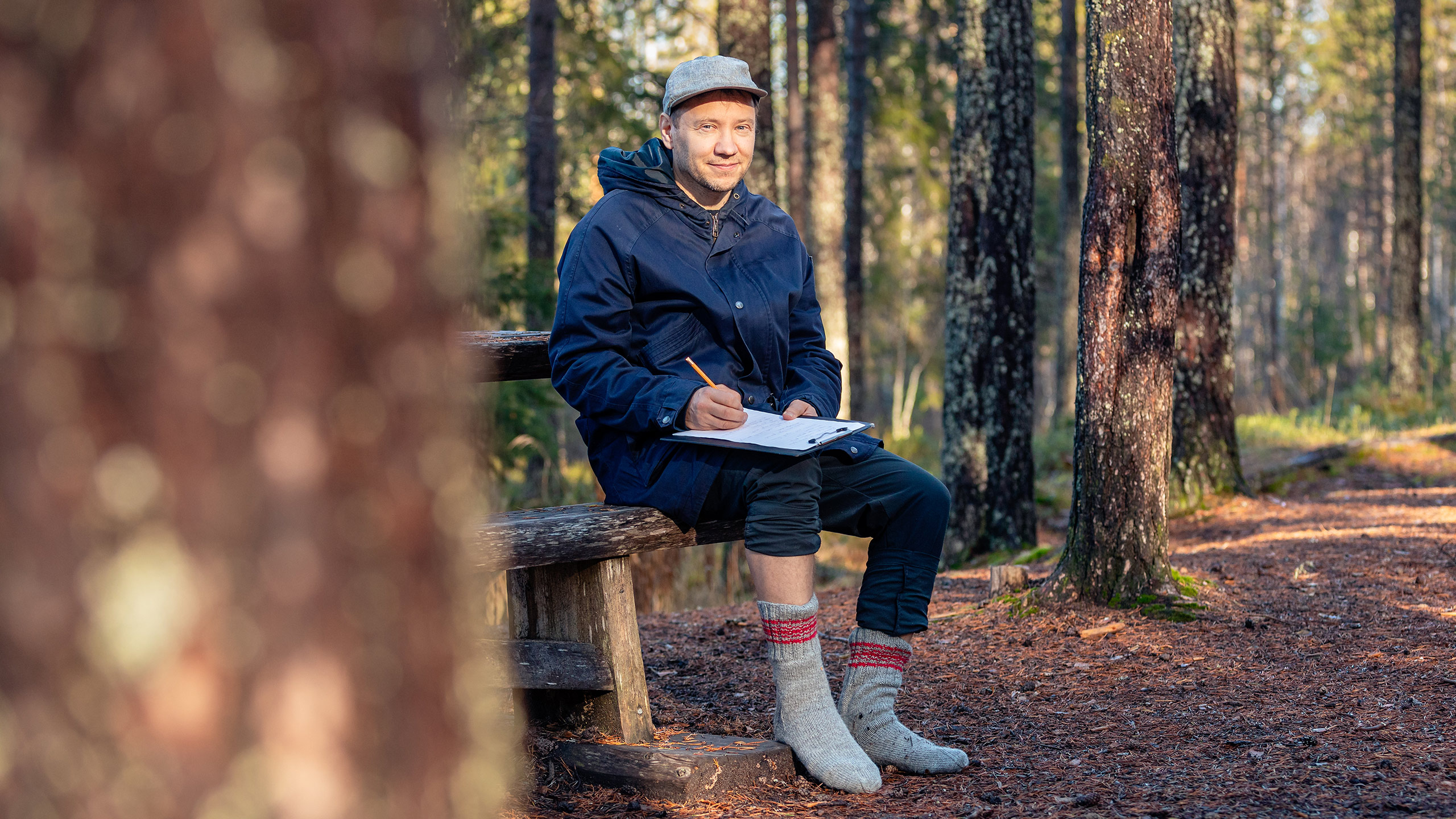 Jaakko Ruuskaa istuu syksyisessä metsässä villasukat jalassa.