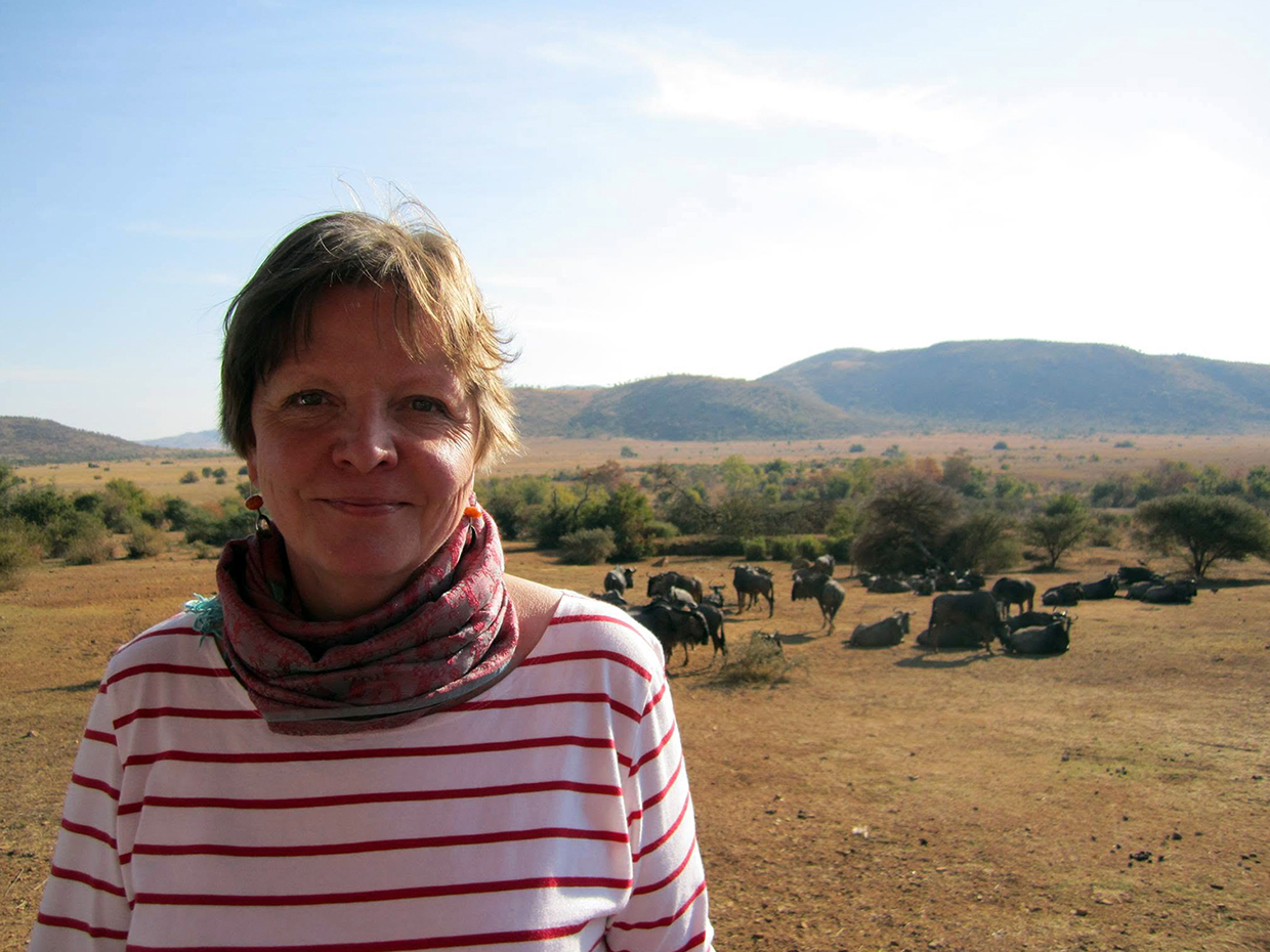 Kristiina Hänninen vuonna 2013 Namibiassa, taustallaan savannia ja lauma gnuantilooppeja.